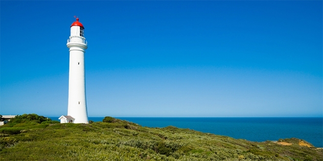 view of split point white lighthouse with its red roof with the sea and sky in the background